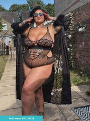 Person wearing a black lace bodysuit outdoors with a house in the background