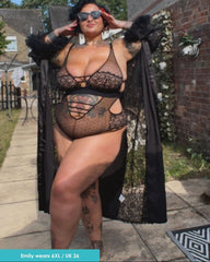 Person wearing a black lace bodysuit outdoors with a house in the background