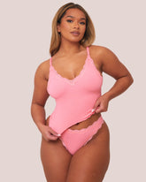 Woman wearing a pink lingerie set against a plain background