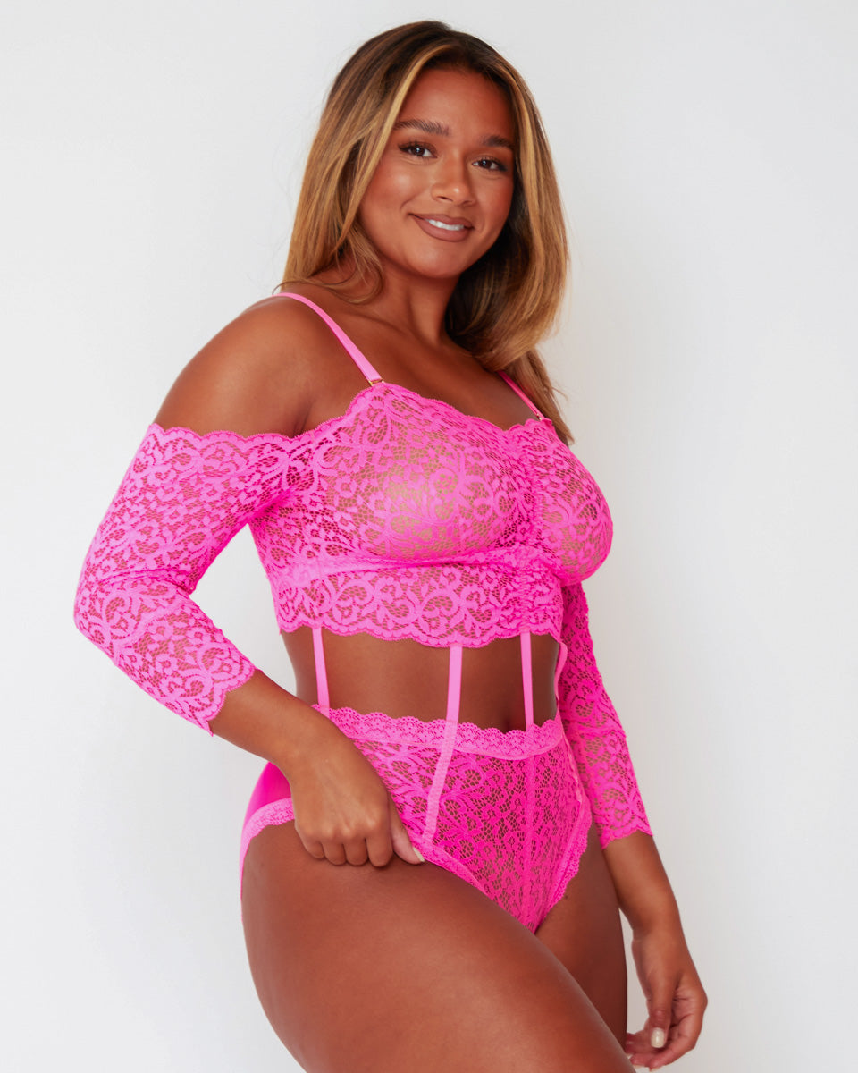 Side profile of the Alix Bodysuit in Pink, highlighting the off-the-shoulder lace sleeves, sheer lace construction, contouring cut-out design, and high-leg fit.