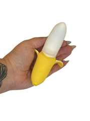 Hand holding a yellow and white banana toy against a white background