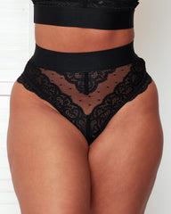 Close-up front view of the Francine Thong in Black by Tutti Rouge, featuring delicate floral lace, sheer dotted mesh panels, a wide elastic waistband, and a flattering high-rise silhouette.