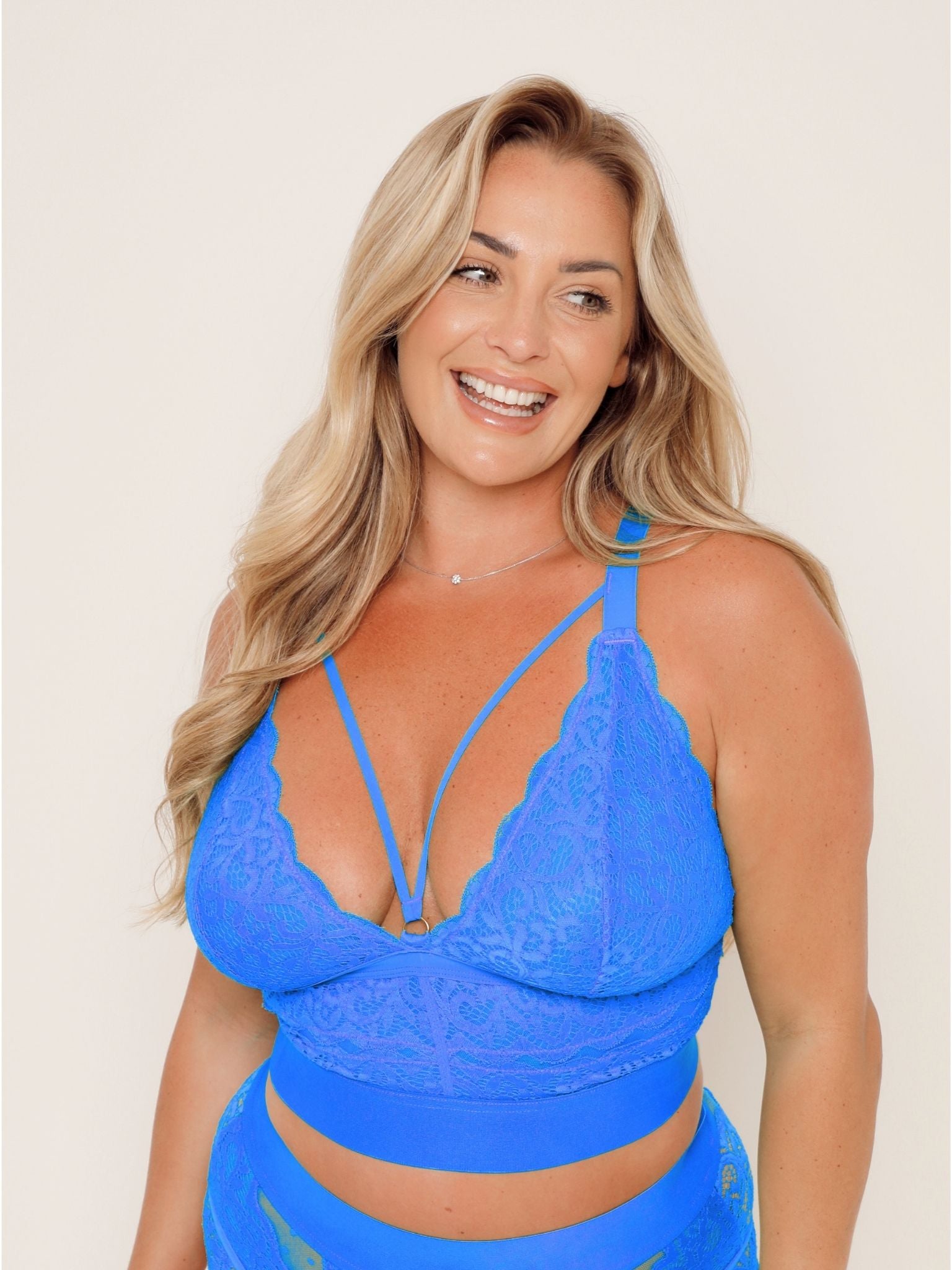 Curve model wearing the Gia Bralette in Dazzling Blue, showcasing soft floral lace cups, a decorative strappy neckline, and a supportive wide underband.
