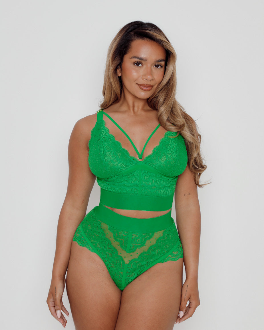 Front view of a model wearing a Harlequin Green lace lingerie set with a plunge lace bralette, decorative strap detail, and matching high-waist briefs designed for fuller bust and curve sizes.